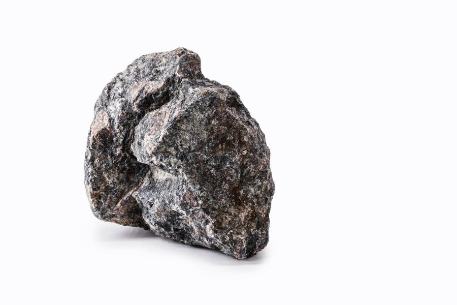 Rocha granítica escura em estúdio com fundo branco isolado