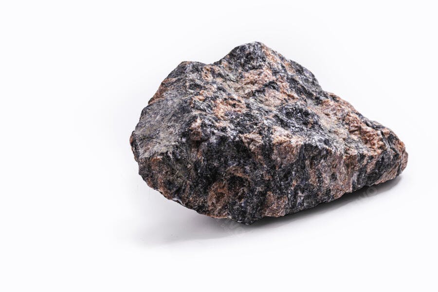 Rocha irregular com minerais escuros e rosados em fundo branco