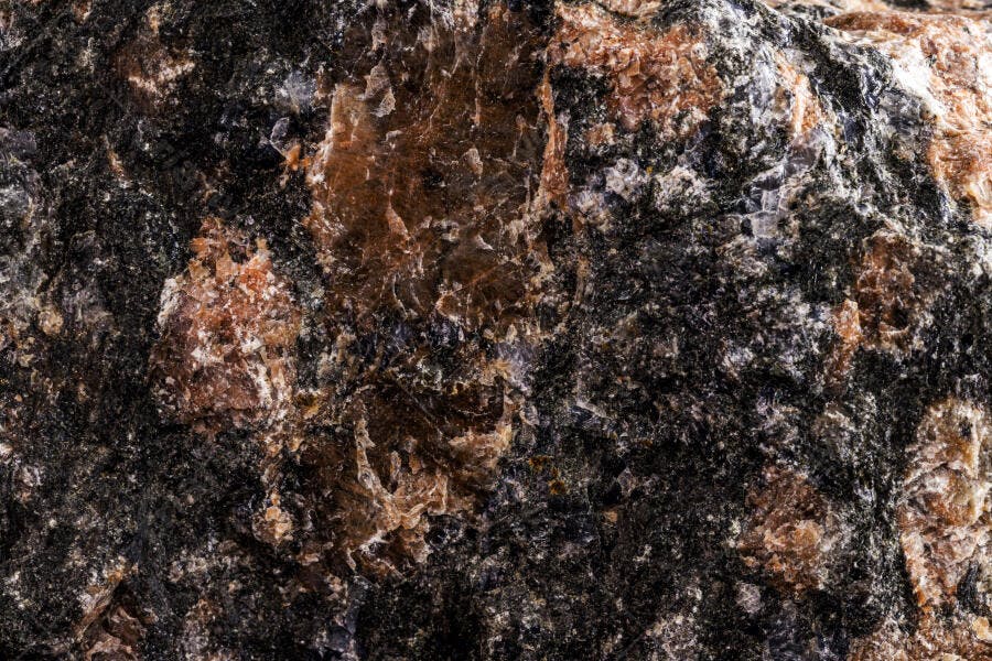 Textura de rocha mineral escura com veios marrom-avermelhados