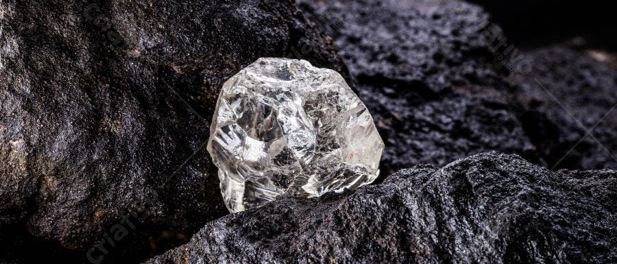 Cristal de quartzo bruto transparente sobre rocha escura e áspera