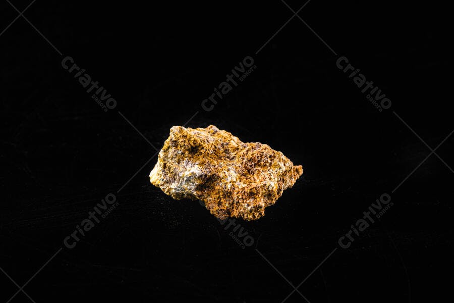 Rocha mineral com textura áspera e tons de laranja marrom em fundo preto isolado