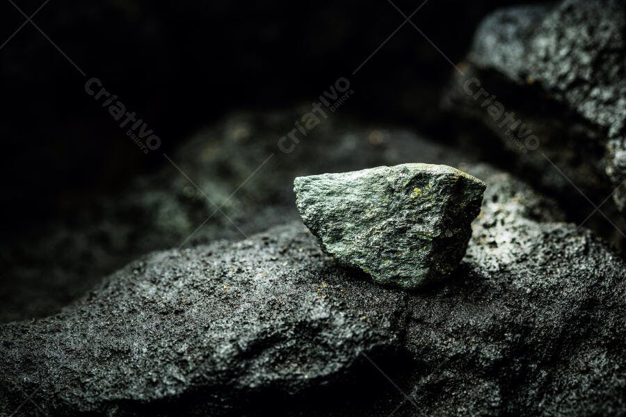 Rocha mineral escura com detalhes verdes e textura áspera