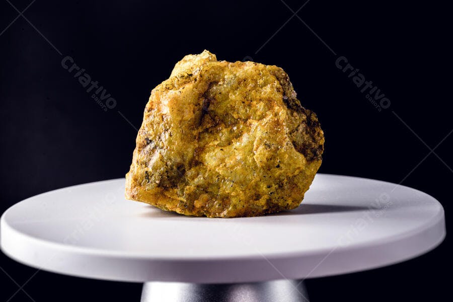 Rocha mineral amarela e verde em pedestal branco com fundo preto