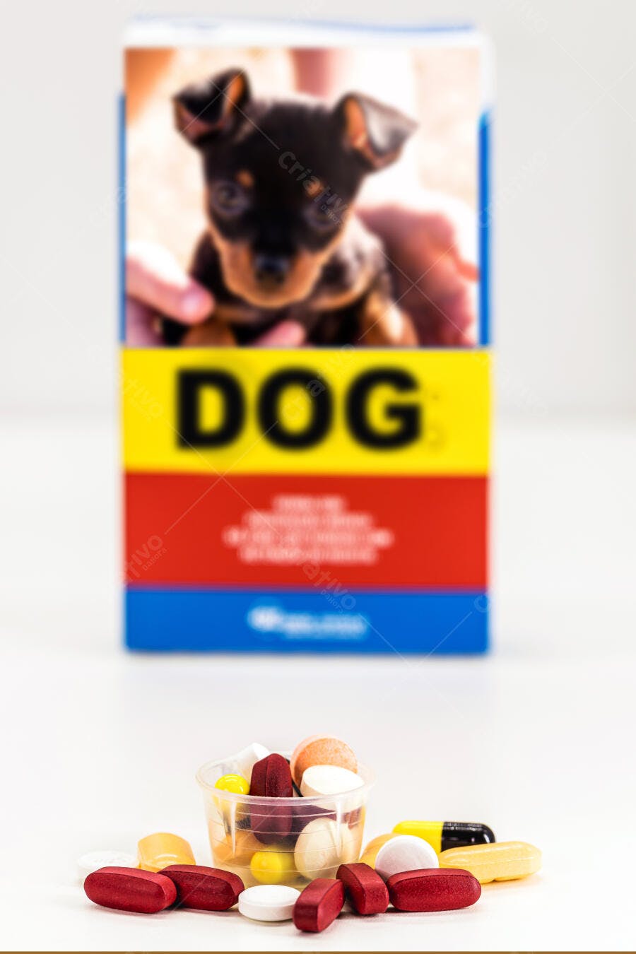 Várias pastilhas e cápsulas para cães em copo dosador com caixa de medicamento pet