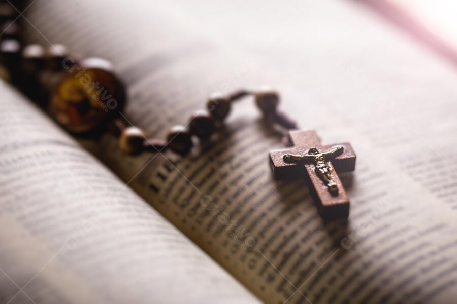 Rosário de madeira e crucifixo dourado sobre a Bíblia sagrada aberta