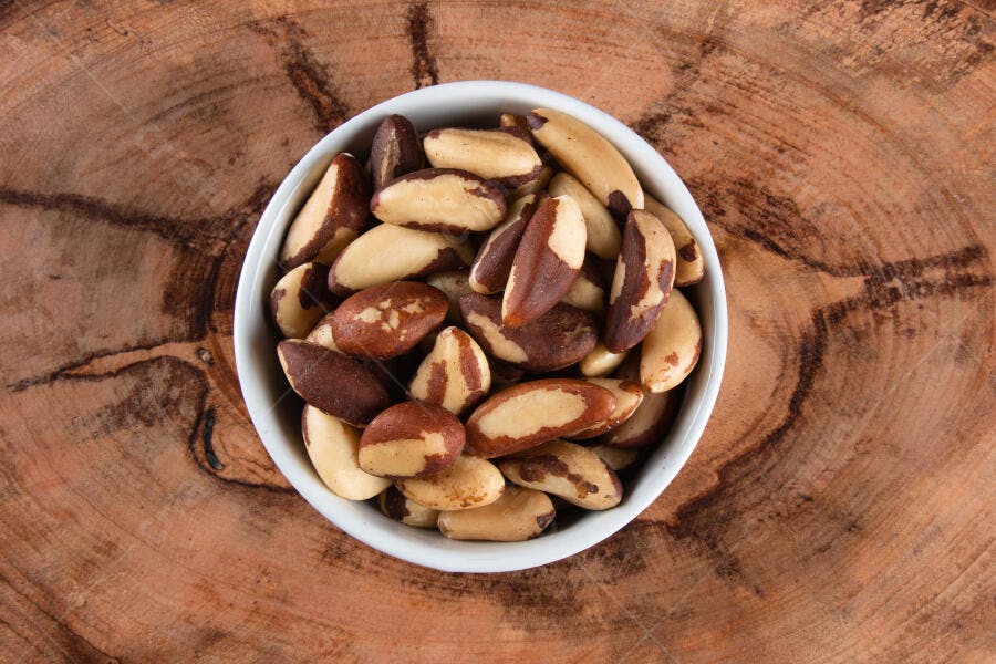 Castanhas-do-pará frescas em tigela branca sobre mesa de madeira rústica