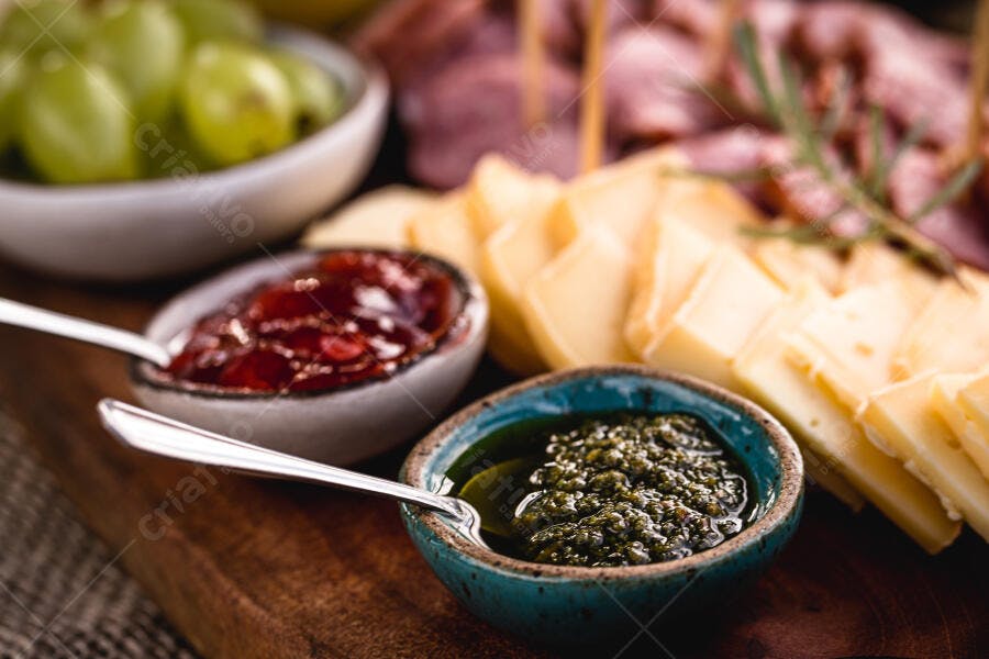 Tábua de queijos e molhos com geleia vermelha pesto e uvas frescas