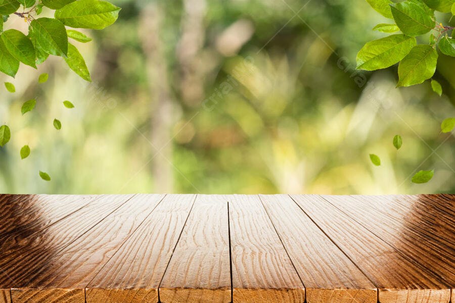 Mesa de madeira rústica com folhas verdes e fundo de natureza borrada