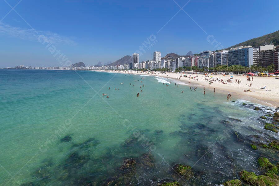 Praia do Rio de Janeiro com pessoas e edifícios mar azul-turquesa ensolarado
