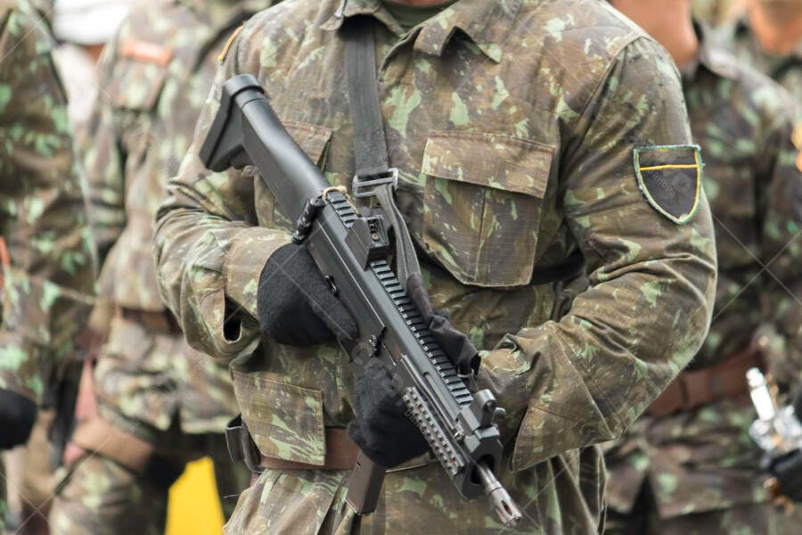 Soldado militar brasileiro em uniforme camuflado segurando fuzil negro