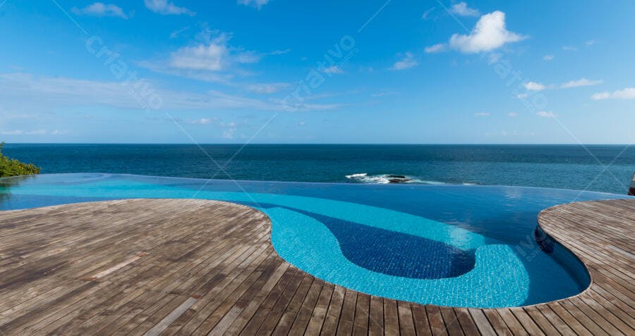 Piscina de borda infinita azul com vista para o mar e deck de madeira