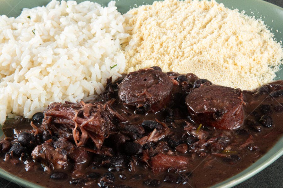 Feijoada completa com arroz branco e farofa em prato verde para almoço tradicional