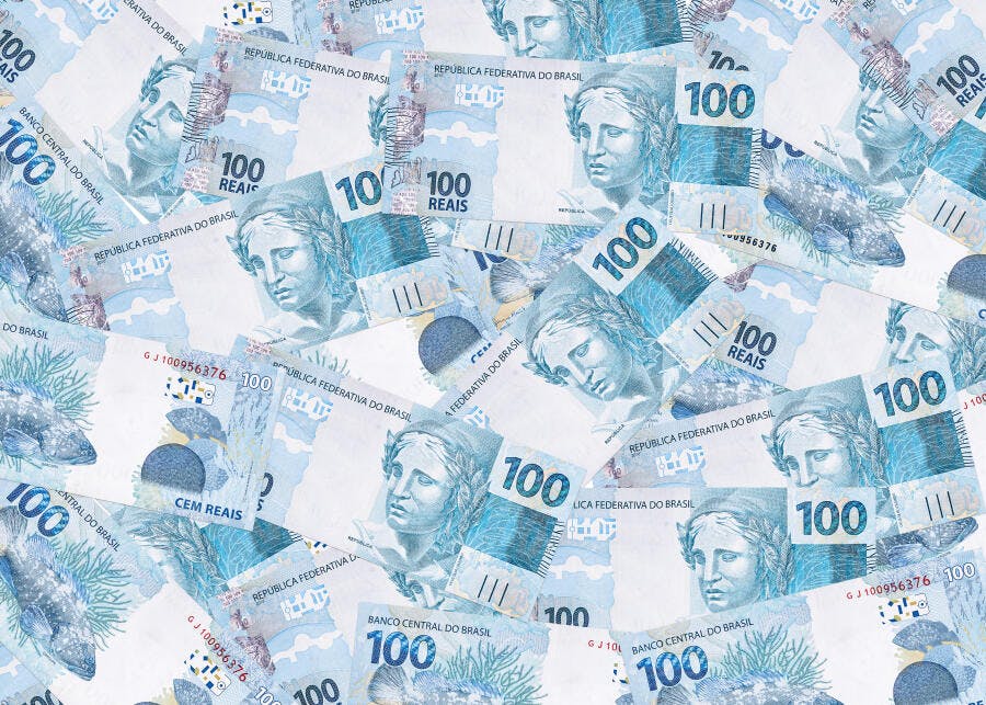 Notas de 100 Reais espalhadas em fundo dinheiro brasileiro