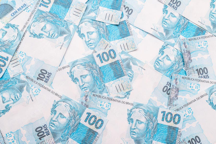 Cédulas de 100 Reais brasileiras espalhadas fundo branco