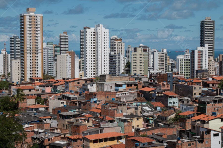 Panorama urbano costeiro com casas simples e arranha-céus modernos na cidade ensolarada