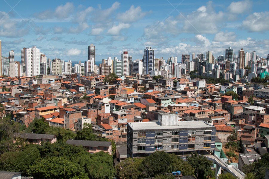 Cidade brasileira com casas populares e arranha-céus sob céu azul