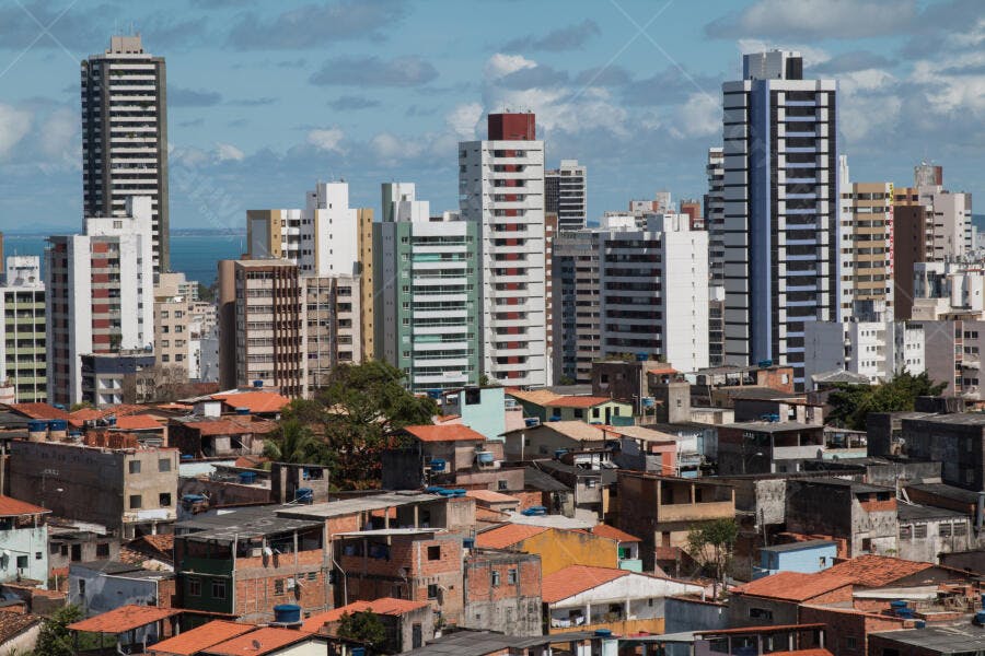 Cidade costeira com prédios altos e casas simples sob céu azul