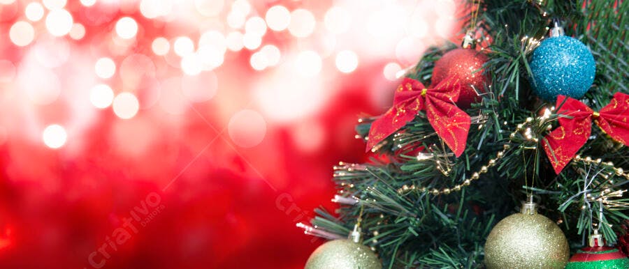 Árvore de Natal verde decorada com bolas vermelhas douradas laços e fundo bokeh vermelho