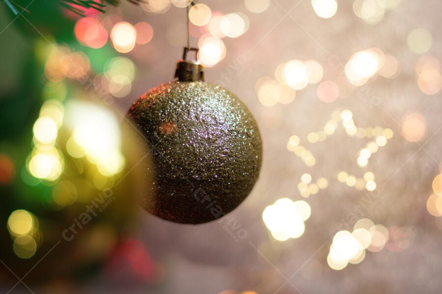 Enfeite de Natal cintilante pendurado em árvore decorada com luzes bokeh coloridas
