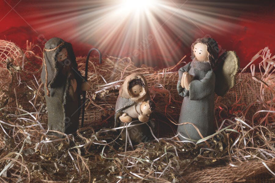 Presépio de Natal figuras de tecido tons terrosos no feno com luz celestial