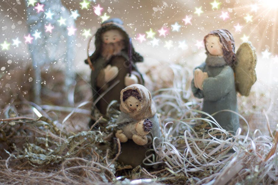 Cena de presépio artesanal com José Maria Jesus e anjo entre palha sob estrelas de Natal