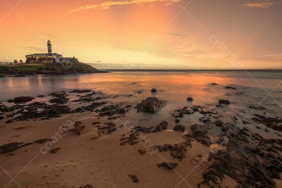 Farol histórico iluminado na costa rochosa ao pôr do sol ou amanhecer