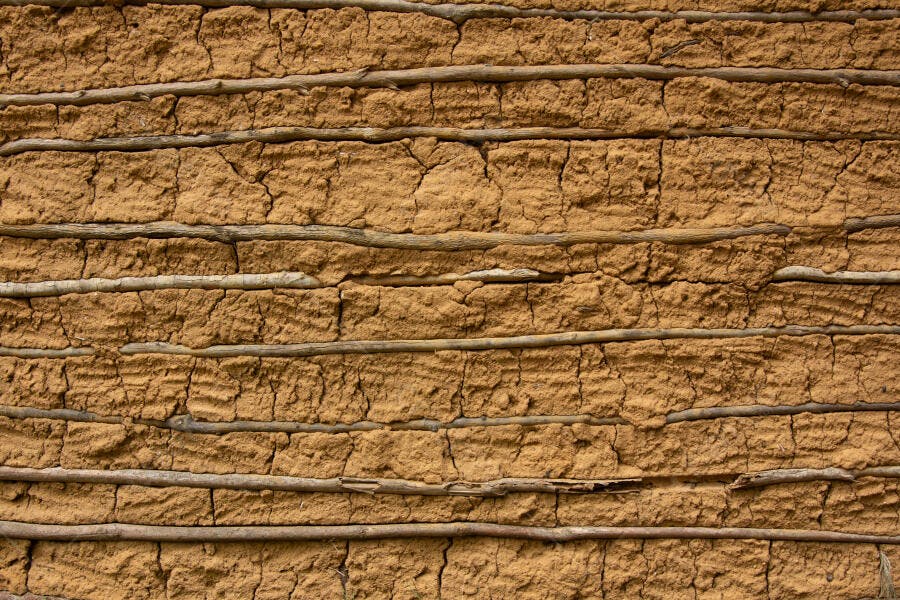 Textura de parede de barro rústica com galhos de madeira e rachaduras