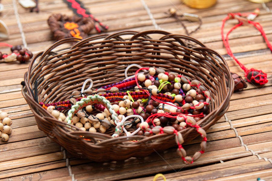 Cesta de vime com pulseiras artesanais coloridas e colares de sementes e búzios