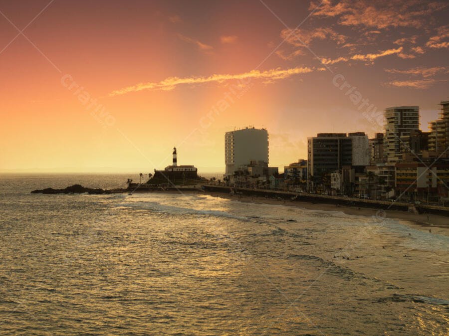 Pôr do sol vibrante no Farol da Barra Salvador Bahia sobre o oceano e cidade costeira
