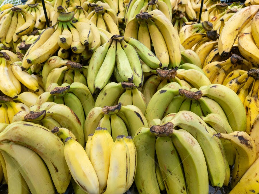 Pilha de bananas frescas amarelas e verdes em exibição no mercado