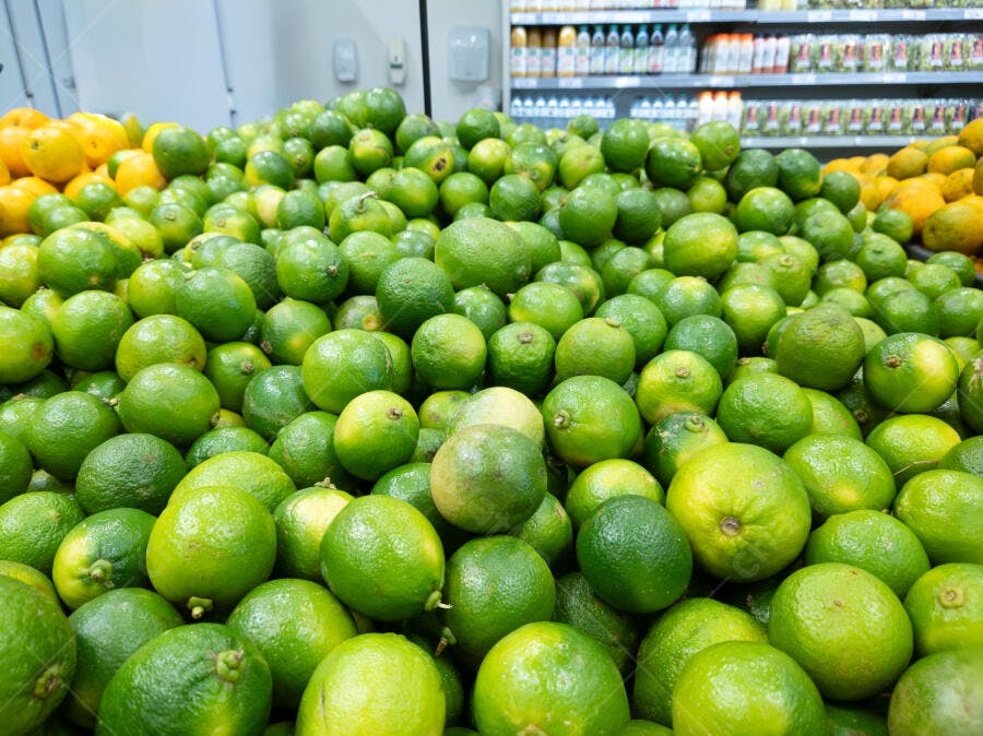 Limas verdes frescas em abundância na prateleira do supermercado