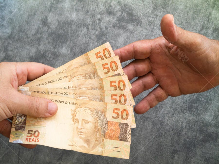 Mãos trocando notas de cinquenta reais do Brasil em transação financeira