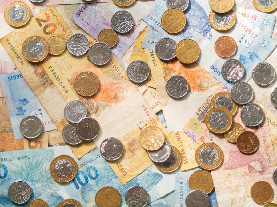 Dinheiro brasileiro Reais notas e moedas espalhadas vista superior