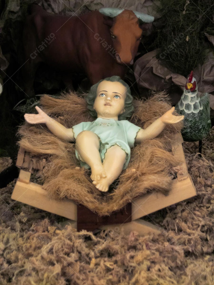 Menino Jesus em presépio natalino com boi e galinha palha e tons terrosos