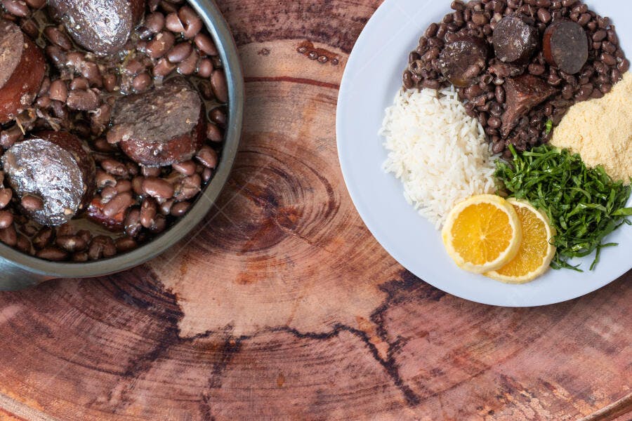 Feijoada tradicional brasileira servida em panela e prato sobre madeira rústica