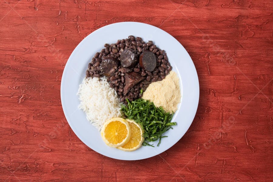 Feijoada brasileira completa com arroz feijão couve farofa e laranja em mesa rústica vermelha