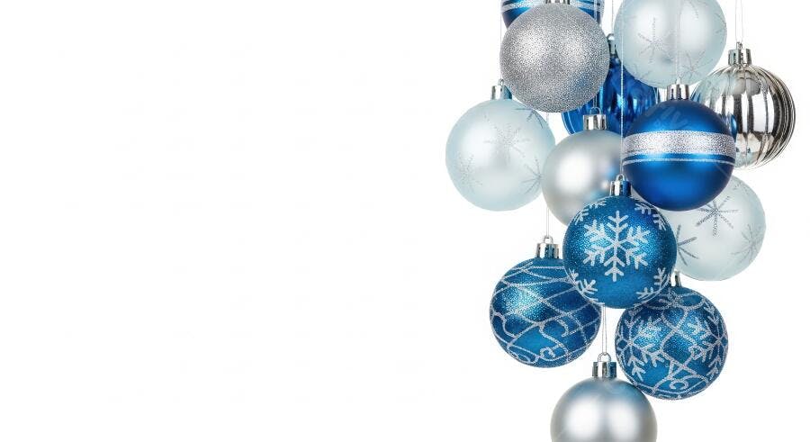 Enfeites de Natal azuis e prateados pendurados em fundo branco