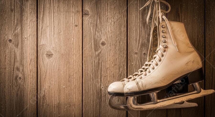 Patins de gelo vintage brancos pendurados em parede de madeira rústica