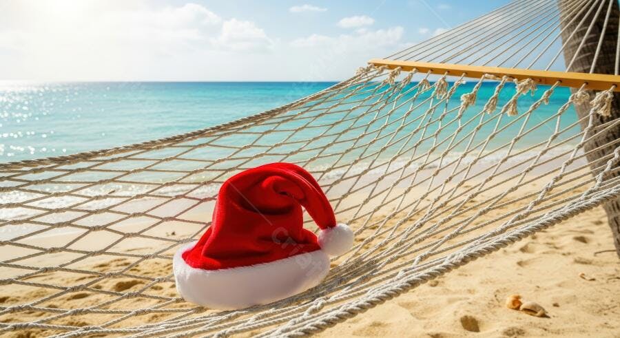 Chapéu de Papai Noel em rede de praia tropical com mar azul cristalino