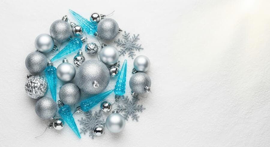 Enfeites de Natal prateados e azuis dispostos em círculo na neve