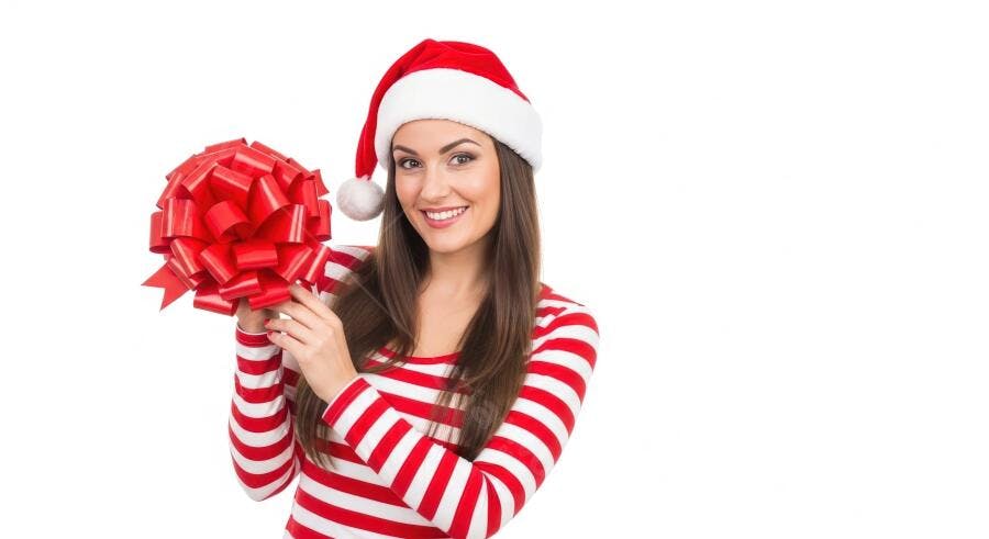 Mulher sorridente com gorro de Papai Noel e laço vermelho de presente
