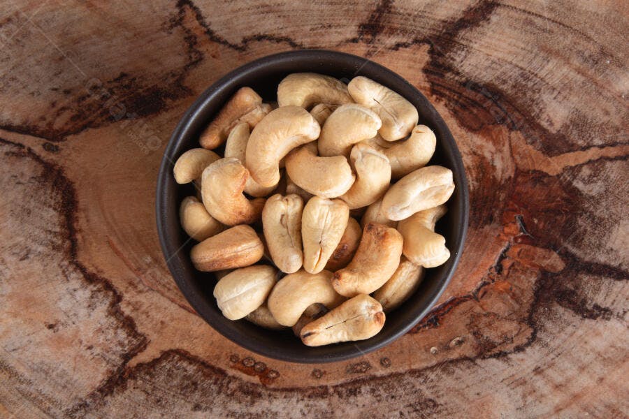Castanhas de caju frescas em tigela rústica sobre fundo de madeira