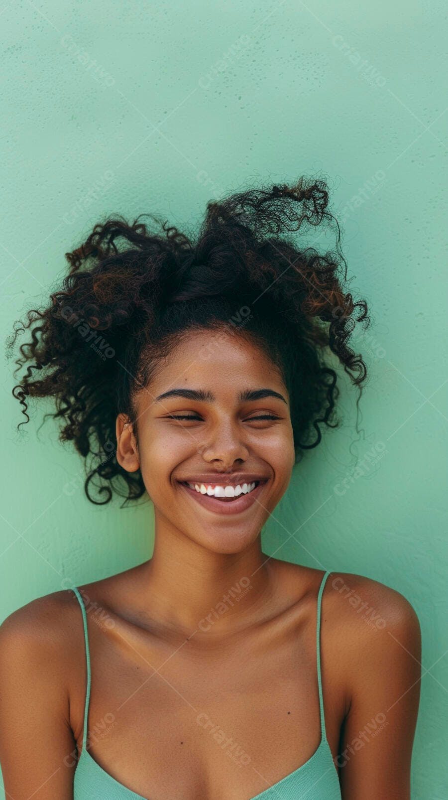 Mulher negra feliz com cabelo cacheado e olhos fechados em fundo verde menta