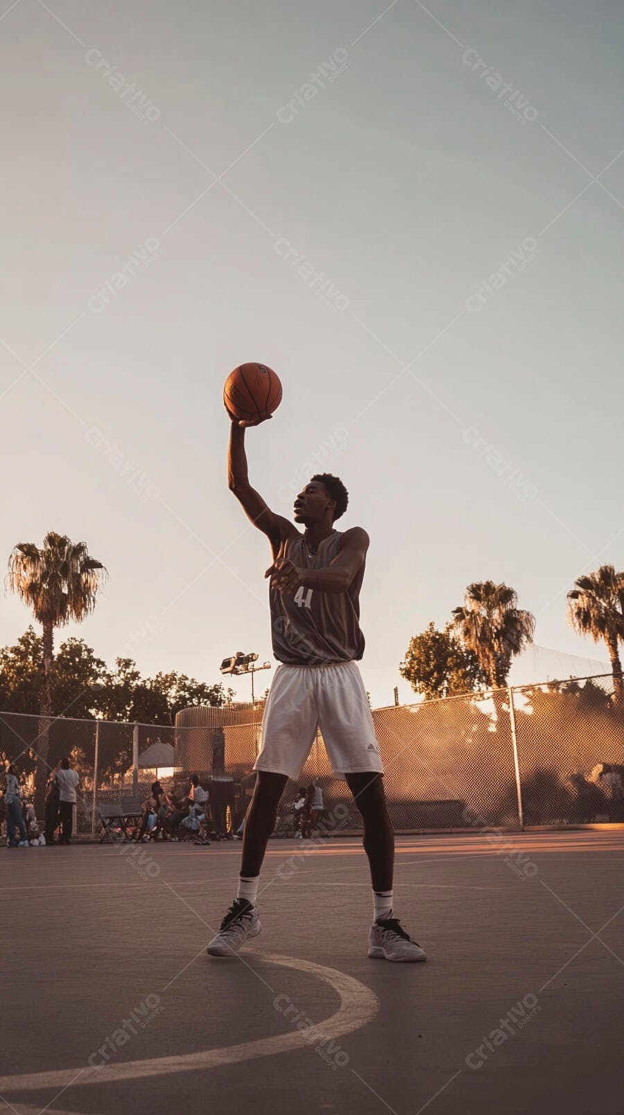 Homem negro arremessando bola de basquete na quadra ao pôr do sol