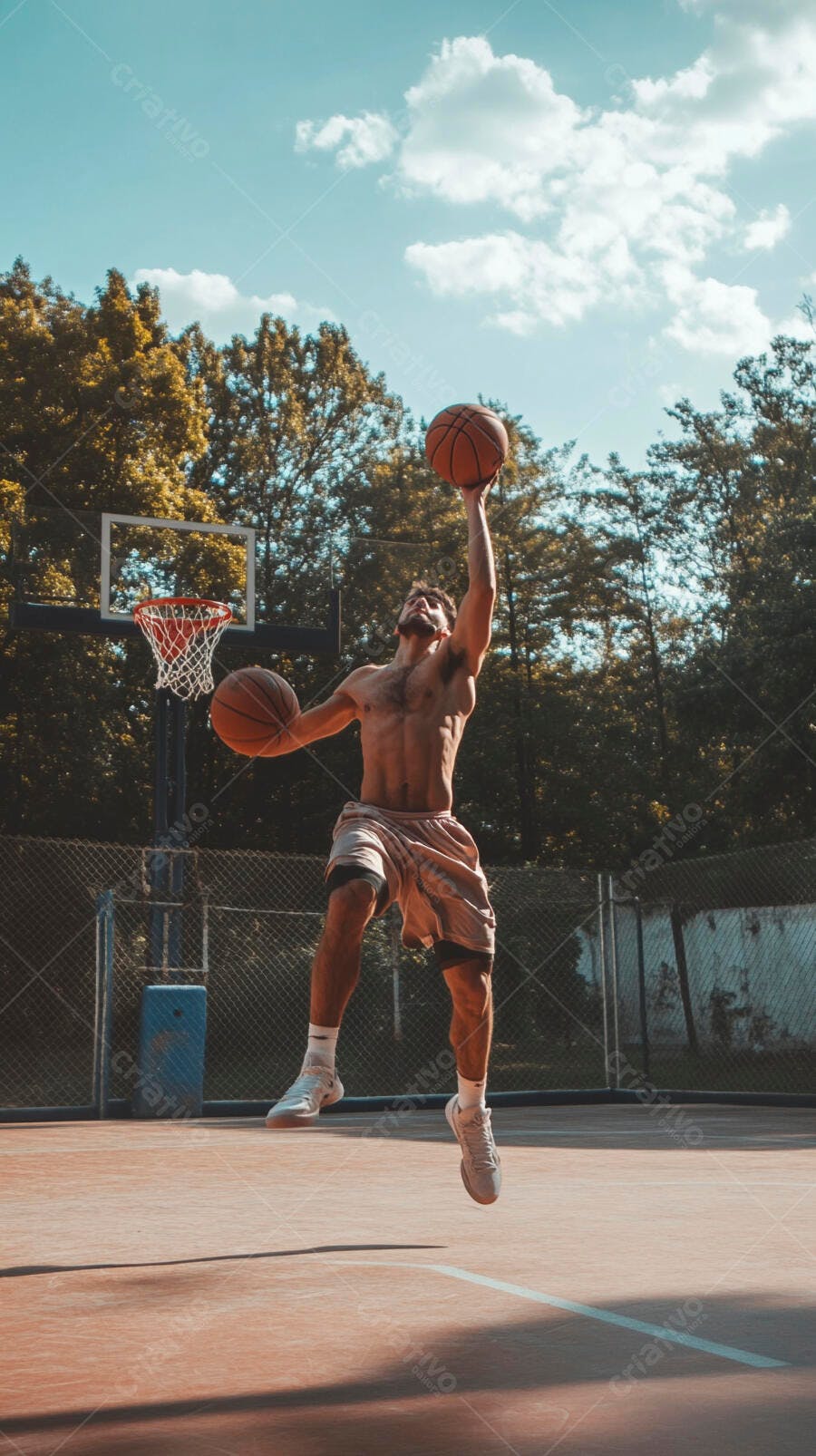 Homem atlético sem camisa saltando com duas bolas de basquete em quadra ensolarada
