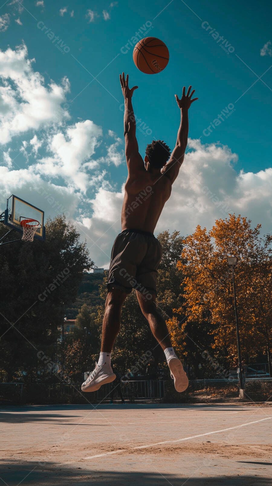 Homem atlético negro saltando com basquete em quadra ao ar livre outono