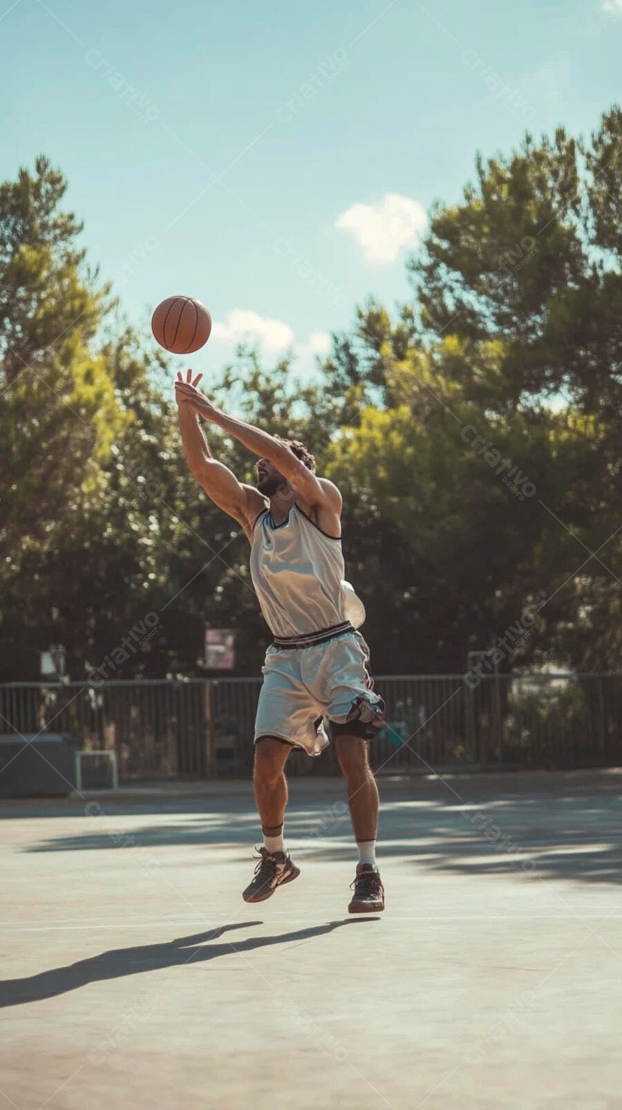Homem atlético barbudo joga basquete em quadra ao ar livre ensolarada