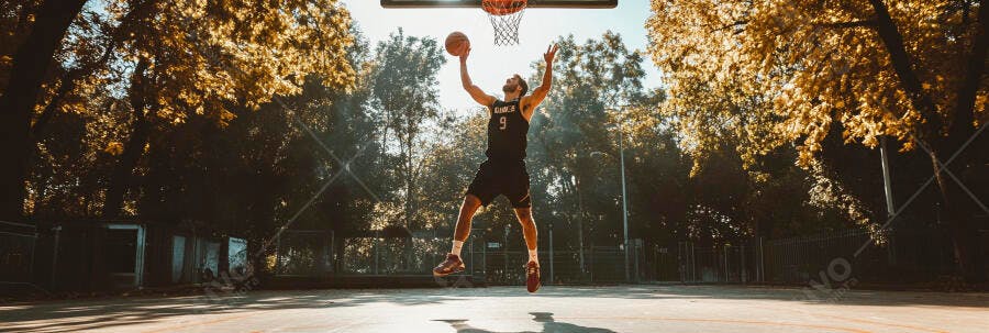 Homem atlético enterrando na quadra de basquete sob sol dourado