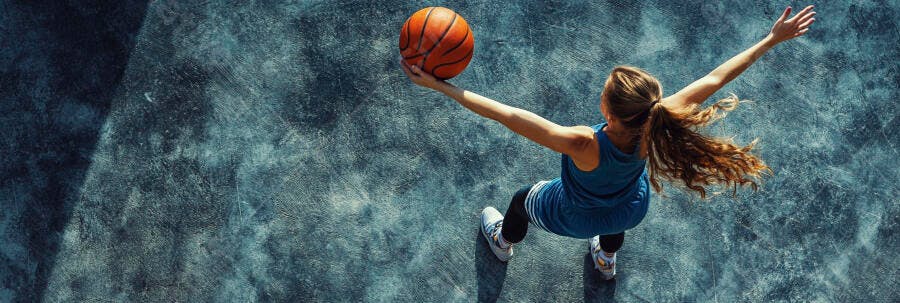 Mulher jovem jogando basquete em quadra azul texturizada vista de cima