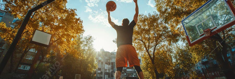 Homem jogando basquete em quadra ensolarada de outono com folhas douradas